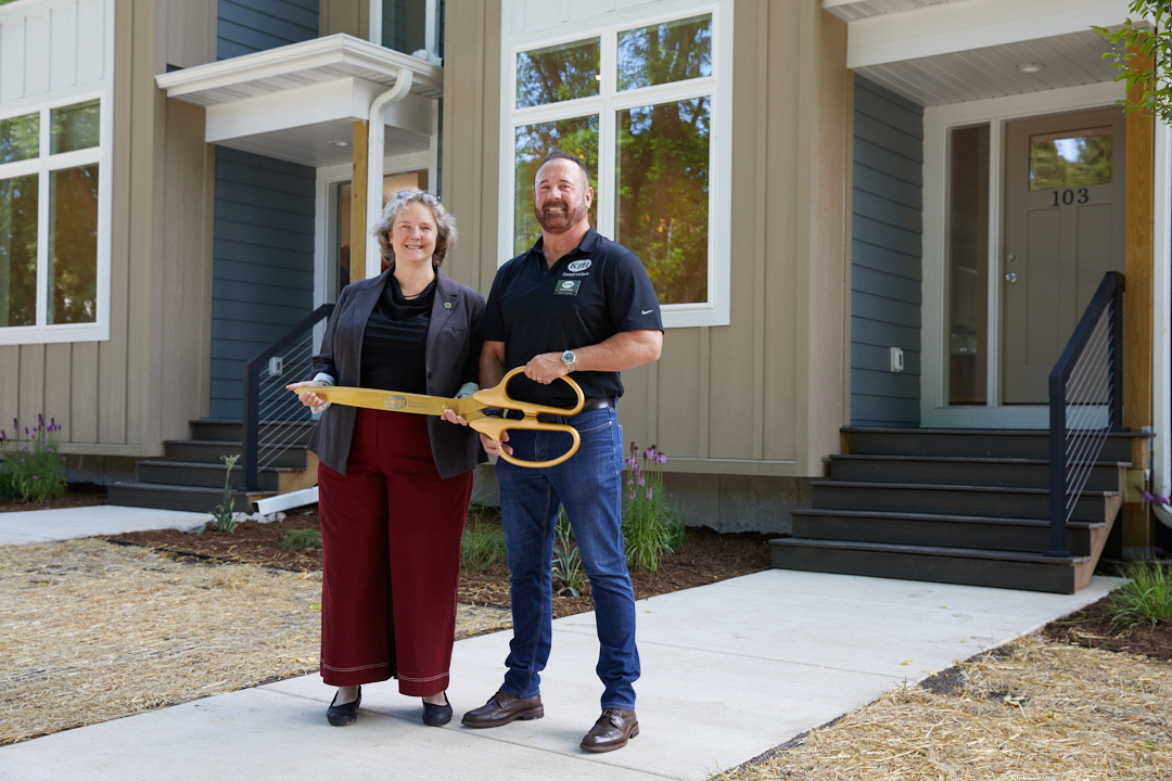 a man and woman holding a large pair of scissors
