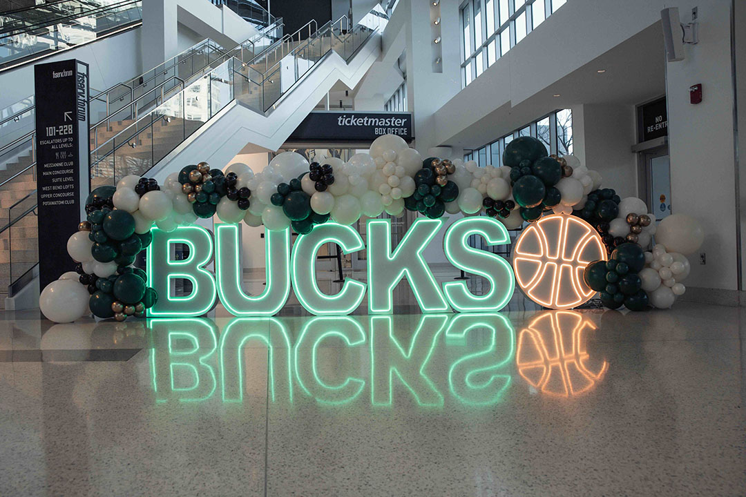 a large neon sign with balloons in front of a building